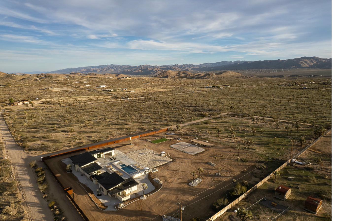 Beachhouse aerial — Joshua Tree forest stretching to mountains