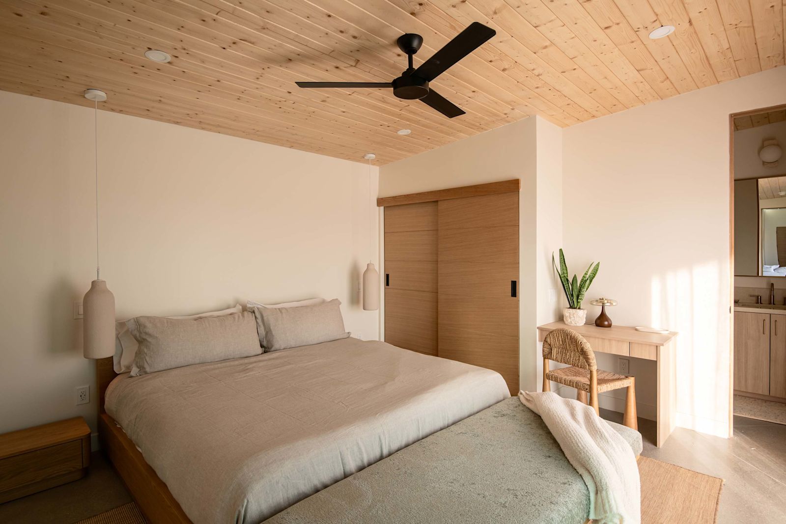 King bedroom with wood-plank ceiling and soft linens