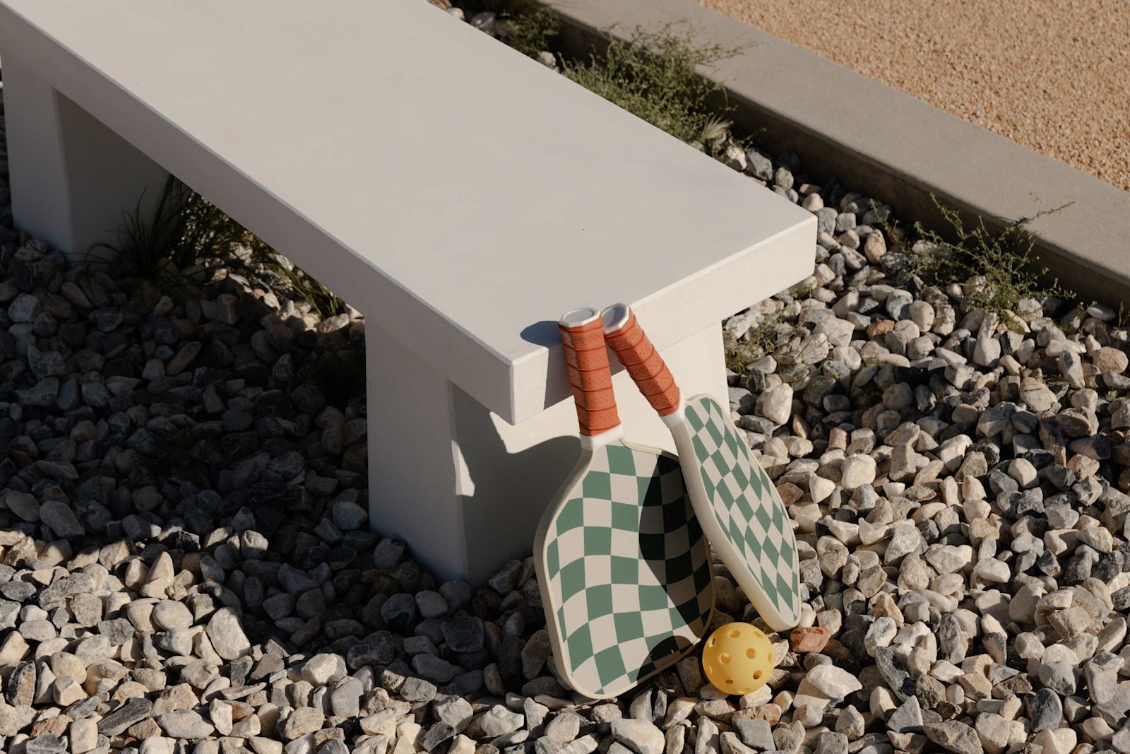Pickleball paddles resting on a bench beside the court