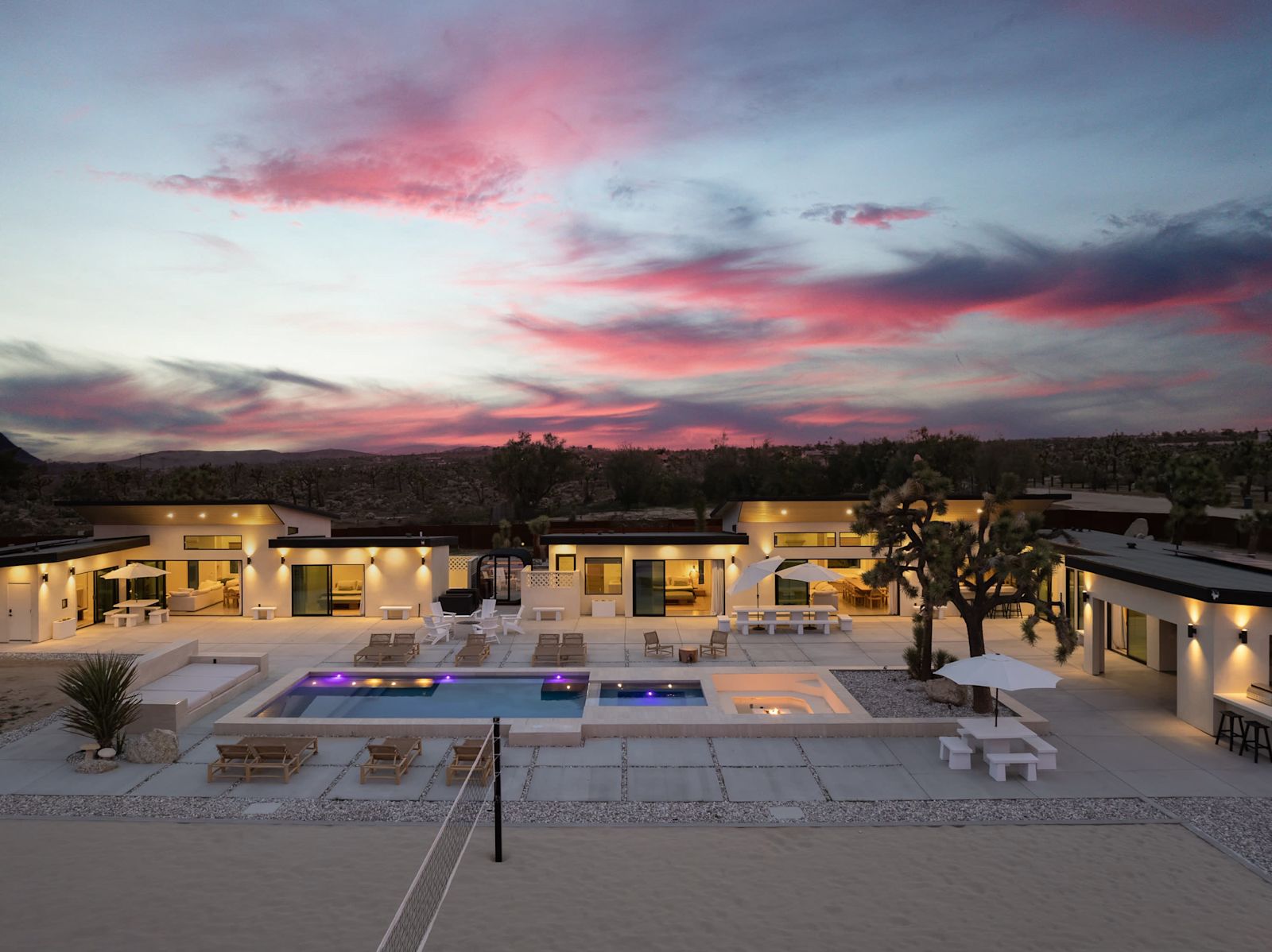 The full Beachhouse compound at dusk with pool and sand court