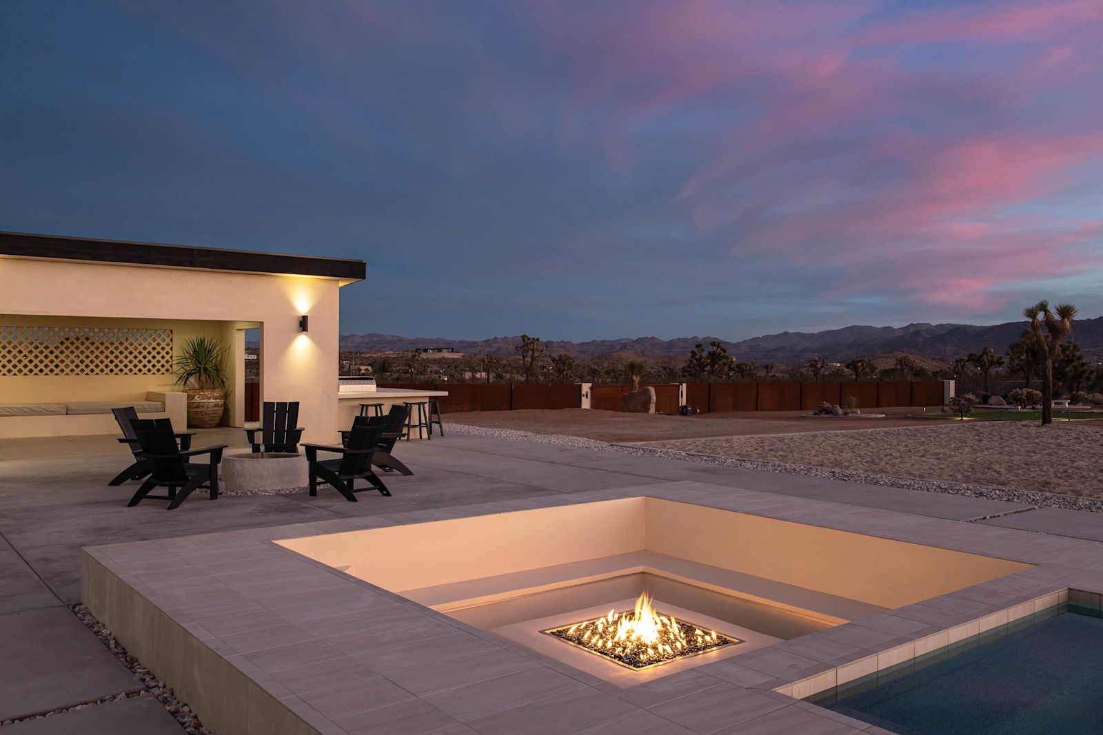 Sunken firepit lounge beside the pool at dusk