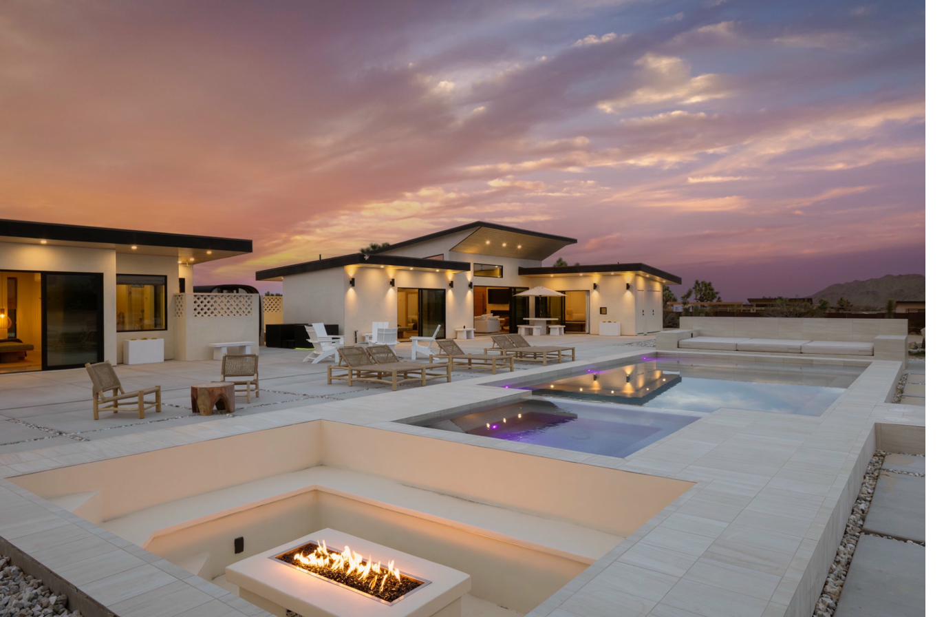 The Sandhouse — pool, firepit, and both homes at golden hour