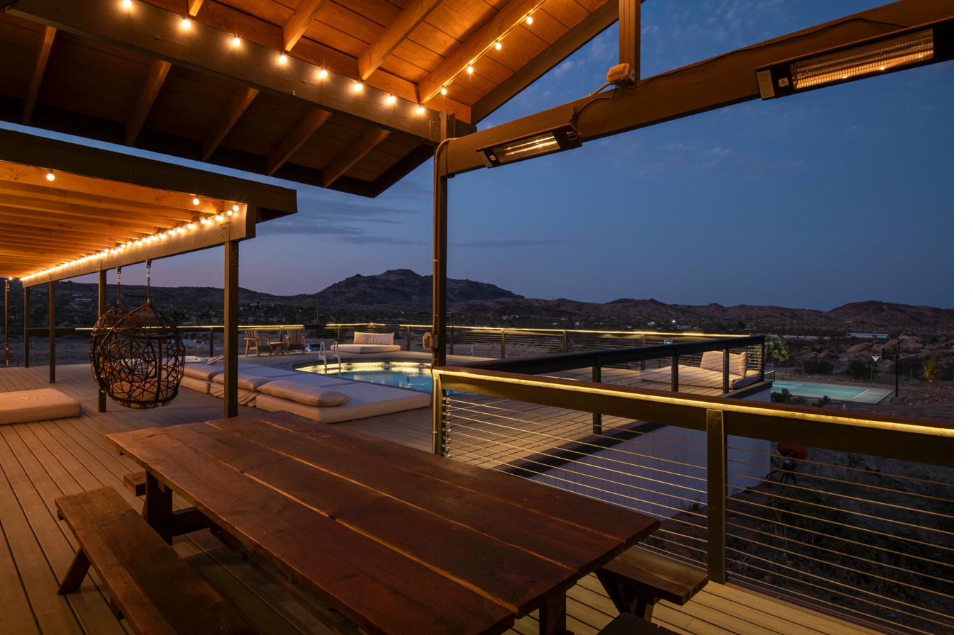String-light covered deck at night overlooking lit pool